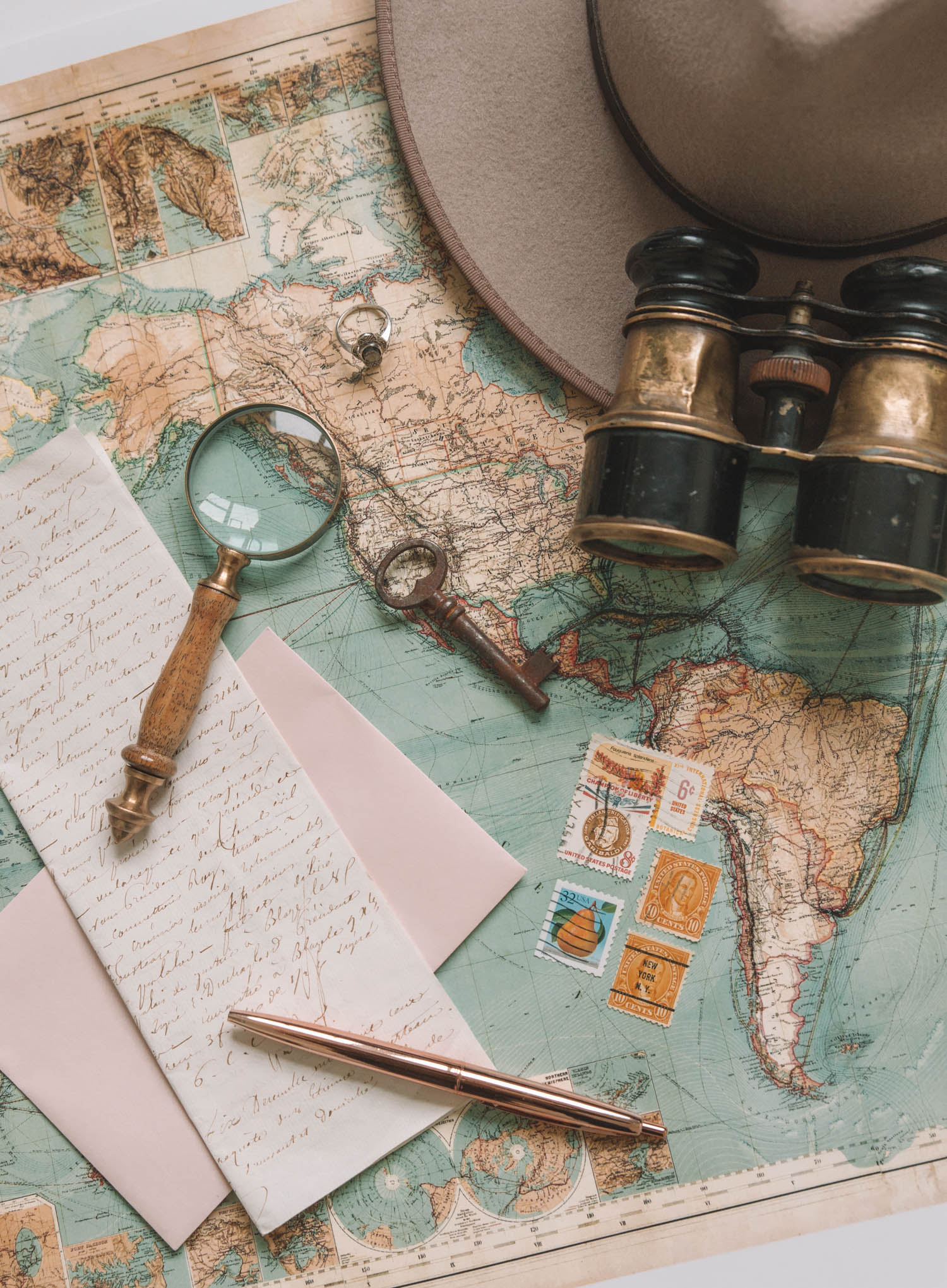Map binoculars vintage letter magnifying glass binoculars wool hat key stamps travel flat lay feminine colonial by product branding photographer Chelsea Loren