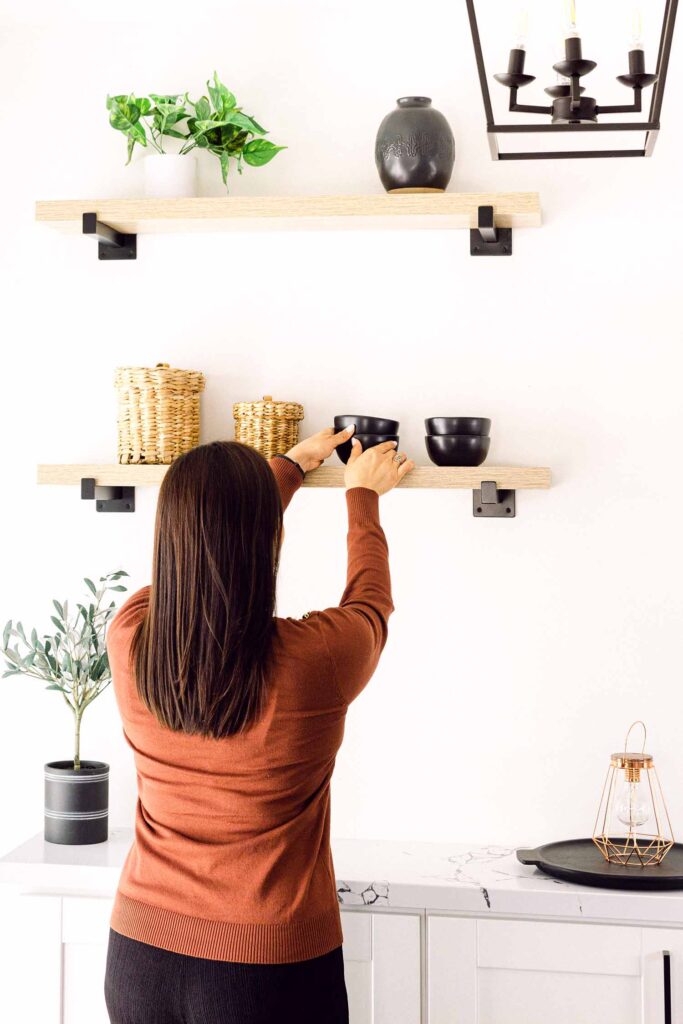 woman cleaning and styling shelves for airbnb photoshoot in southern california