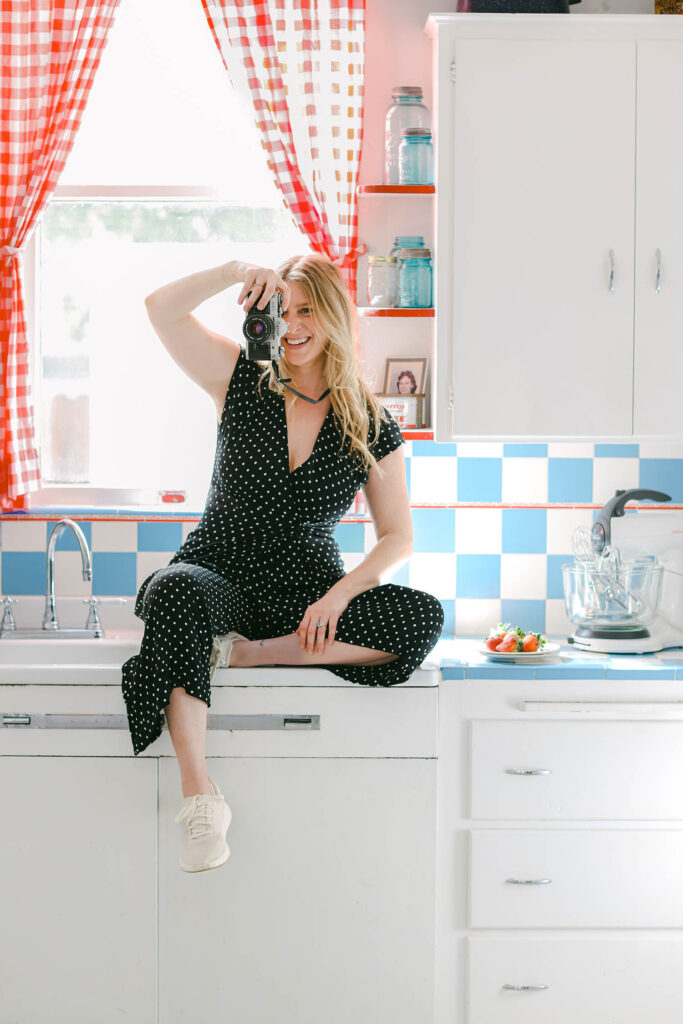 Girl with vintage camera in colorful airbnb kitchen taking photographs southern california