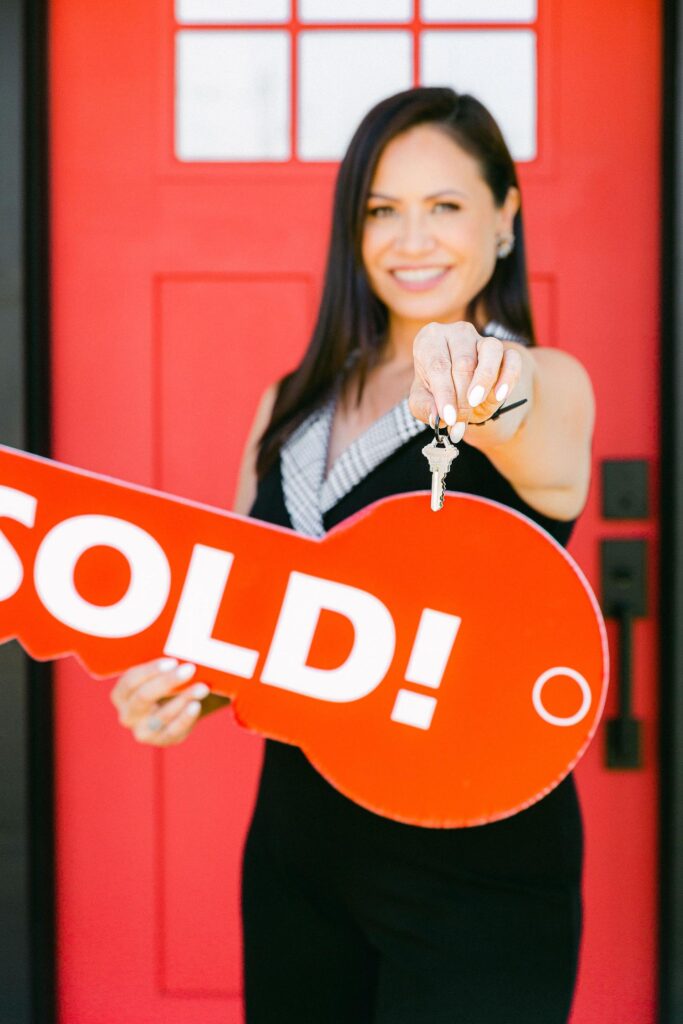 San Diego real estate agent holding up sold sign. Best Personal branding photographer business realtor by Chelsea Loren