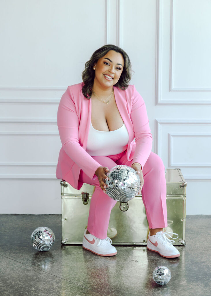 Permanent makeup esthetician boss babe woman powerful and confident in hot pink suit. Joyful personal brand photography with disco balls