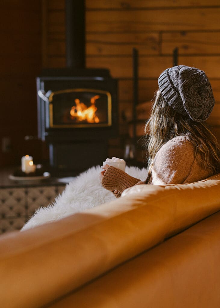 moody airbnb photography girl sitting in front of fire cabin lifestyle photographer