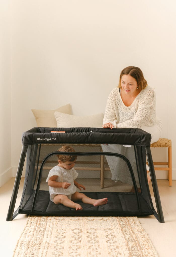 Baby sleeping in a lightweight travel crib in a sunlit hotel room
