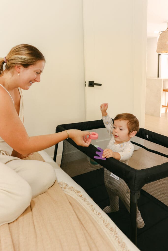 Baby sleeping in a lightweight travel crib in a sunlit hotel room