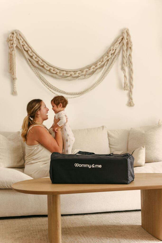baby and mom on couch with portable travel crib zipped up commercial lifestyle photography for luxury kids baby brands