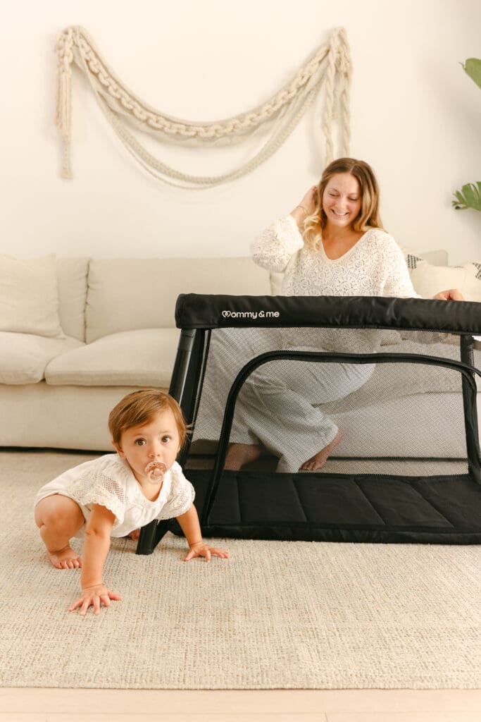 Baby playing in a lightweight travel crib in a sunlit hotel room natural