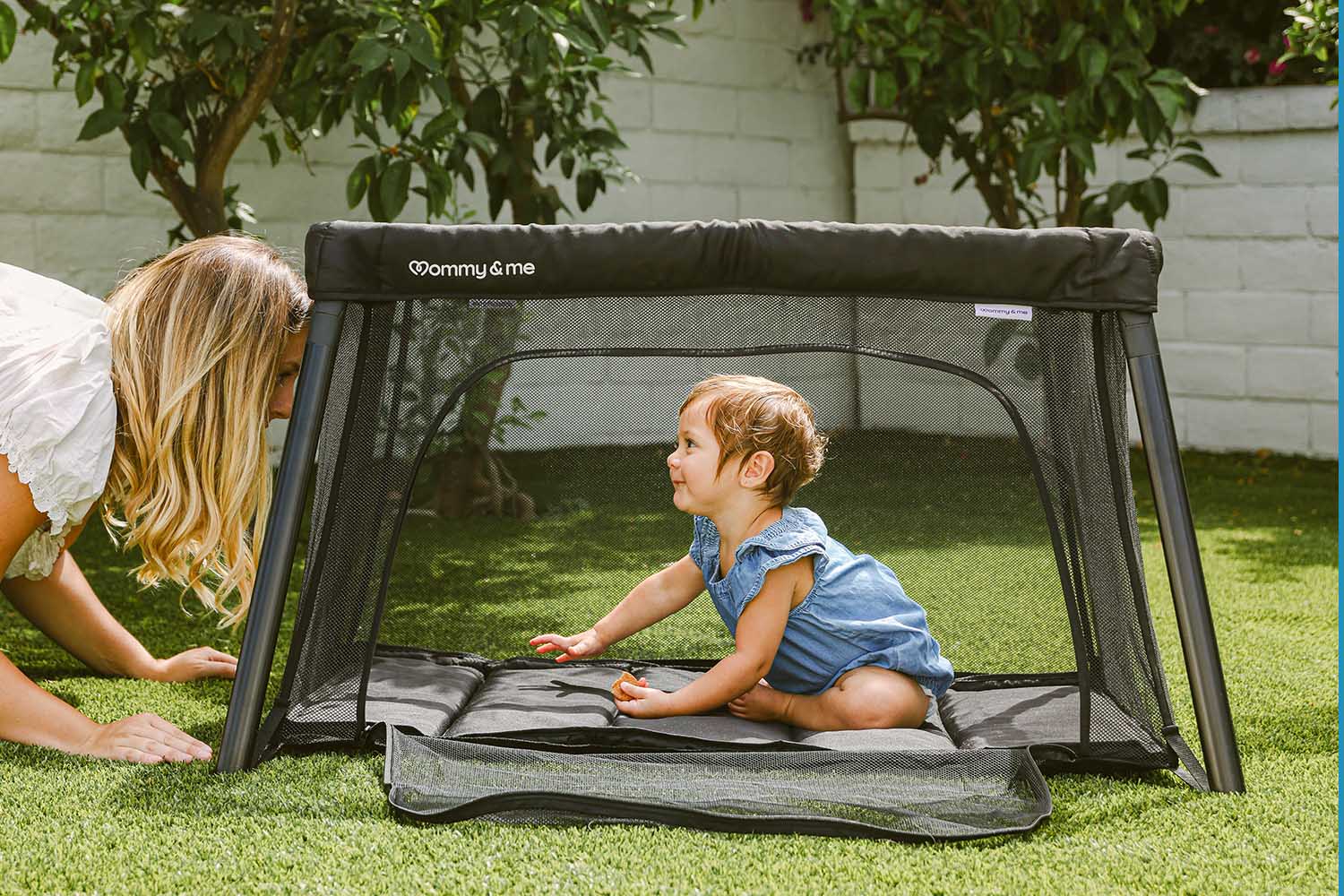 commercial lifestyle photography for a baby travel crib in a backyard featuring mom and baby