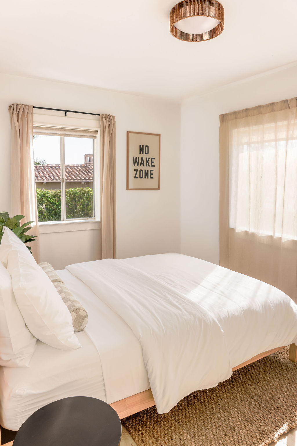 Boutique Airbnb bathroom with teal geometric tile wainscoting, wood vanity, gold faucet, oval mirror, and bubble glass ceiling light in Carlsbad, California, photographed by Chelsea Loren