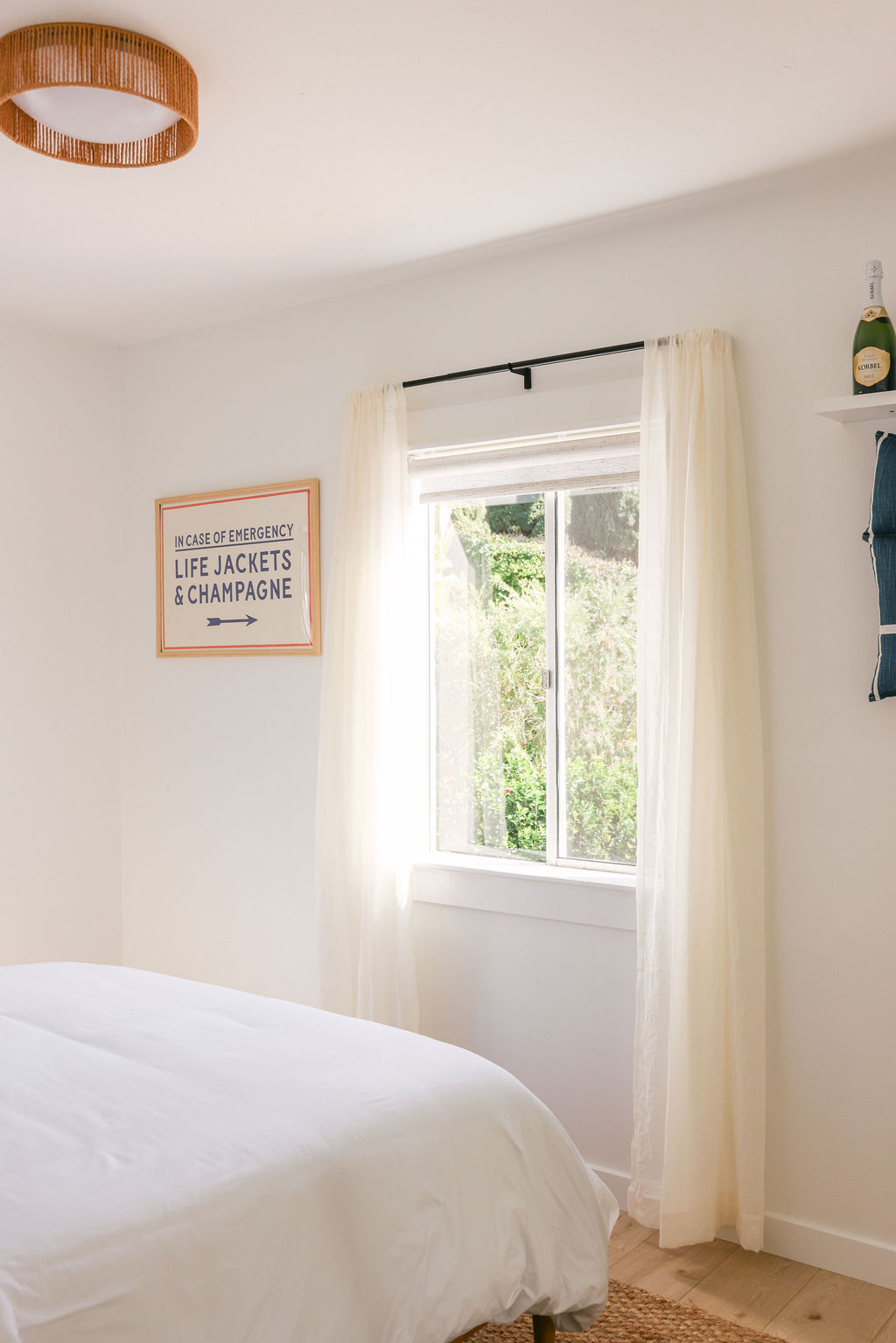 Bright luxury Airbnb living room with blue sofa, wood dining chairs, bird of paradise plant, and panoramic Carlsbad Lagoon views through floor-to-ceiling windows, photographed by Chelsea Loren