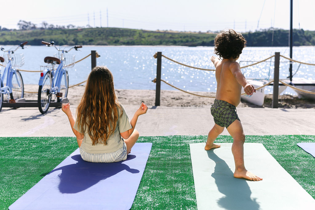 Children doing yoga on outdoor mats by the Carlsbad Lagoon waterfront at a luxury Airbnb in Southern California, photographed by Chelsea Loren