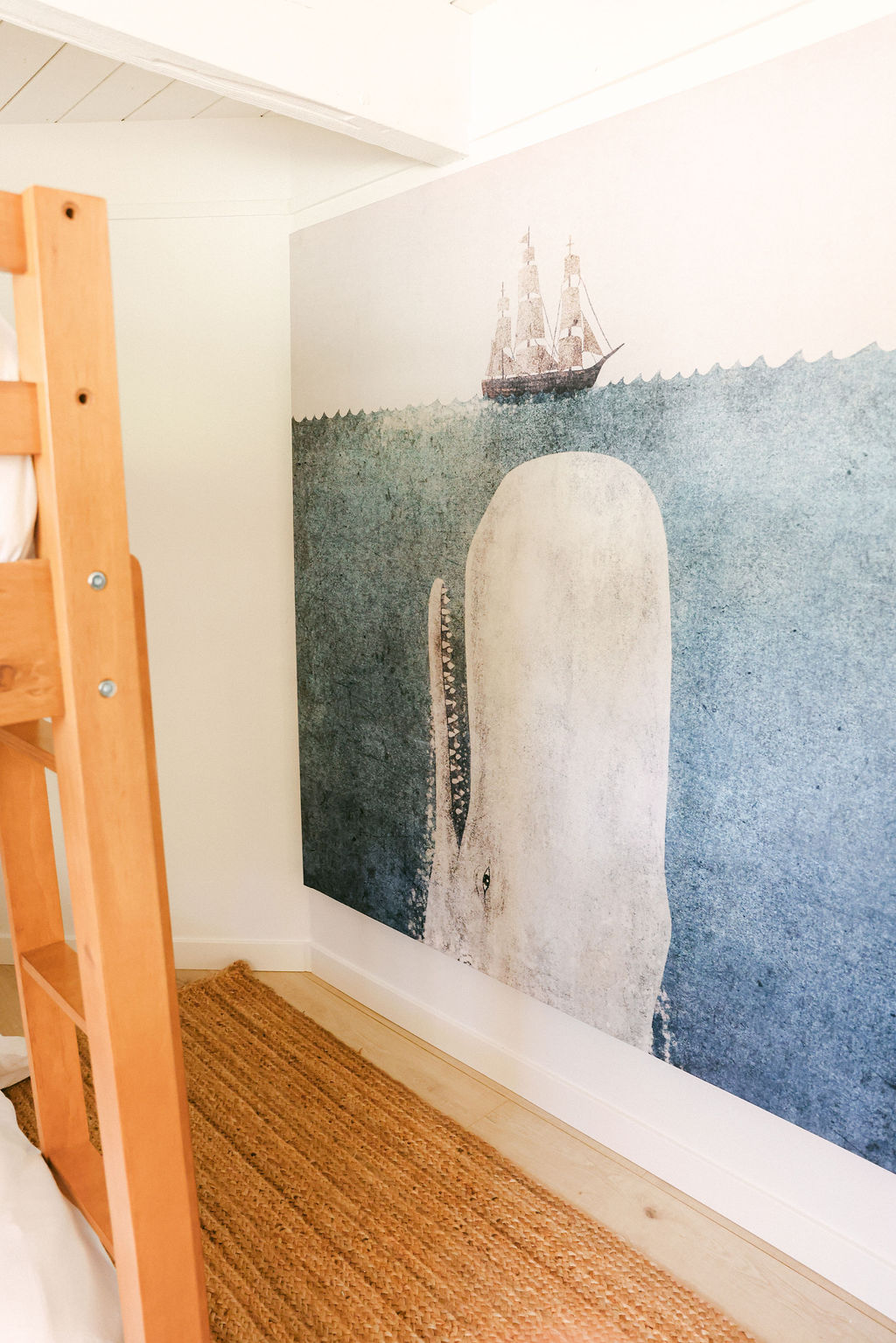 Kids bunk room with a nautical whale and sailing ship wall mural and natural jute rug at a luxury family-friendly Carlsbad Airbnb, photographed by Chelsea Loren