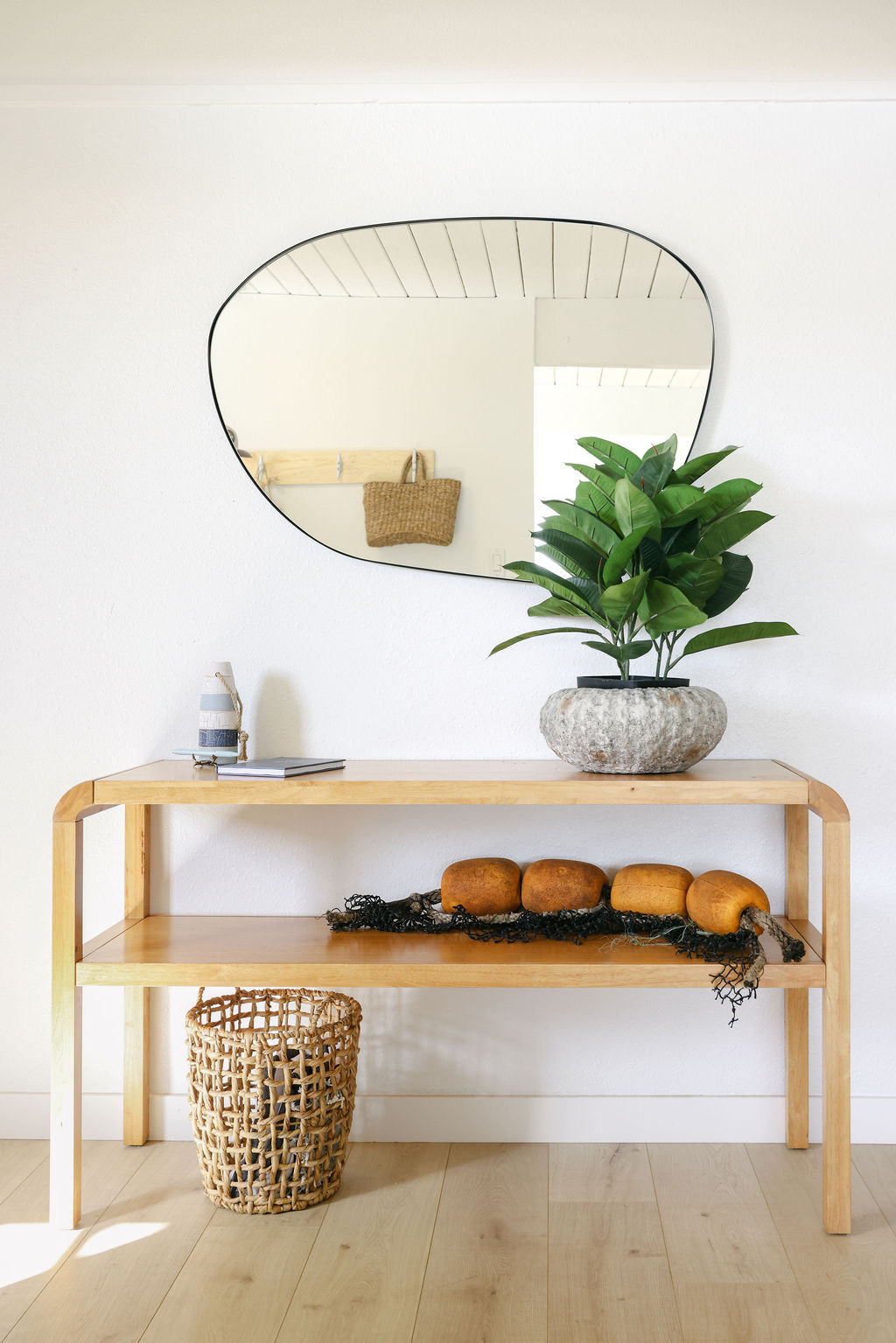 Minimalist coastal interior detail of a wooden console table with organic mirror, ficus plant, and dried botanical decor at a luxury Carlsbad Airbnb, photographed by Chelsea Loren