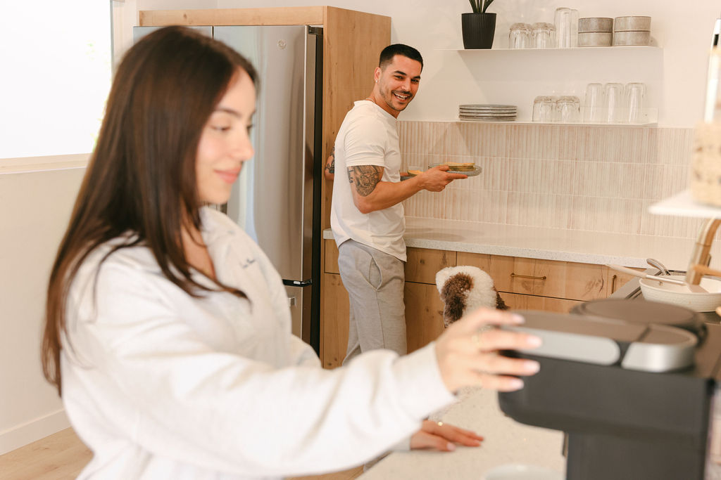 Couple relaxing indoors with a dog while man plays guitar in the sun-filled living room of a luxury Carlsbad Airbnb, lifestyle photography by Chelsea Loren