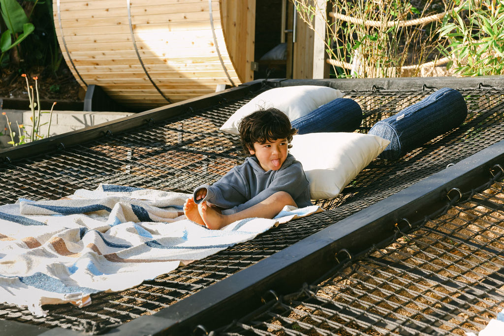 Outdoor barrel sauna and rope hammock surrounded by lush greenery at a luxury Carlsbad Airbnb, elevated short-term rental amenity photography by Chelsea Loren