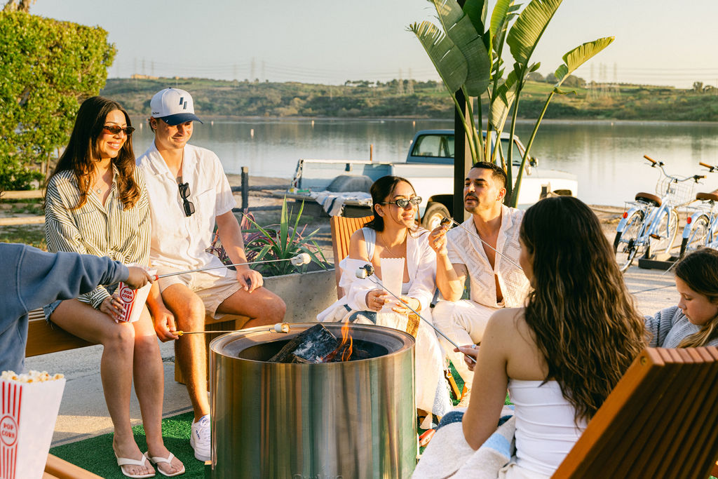 Group of friends roasting marshmallows at a fire pit by the Carlsbad lagoon, luxury Airbnb social lifestyle photography by Chelsea Loren