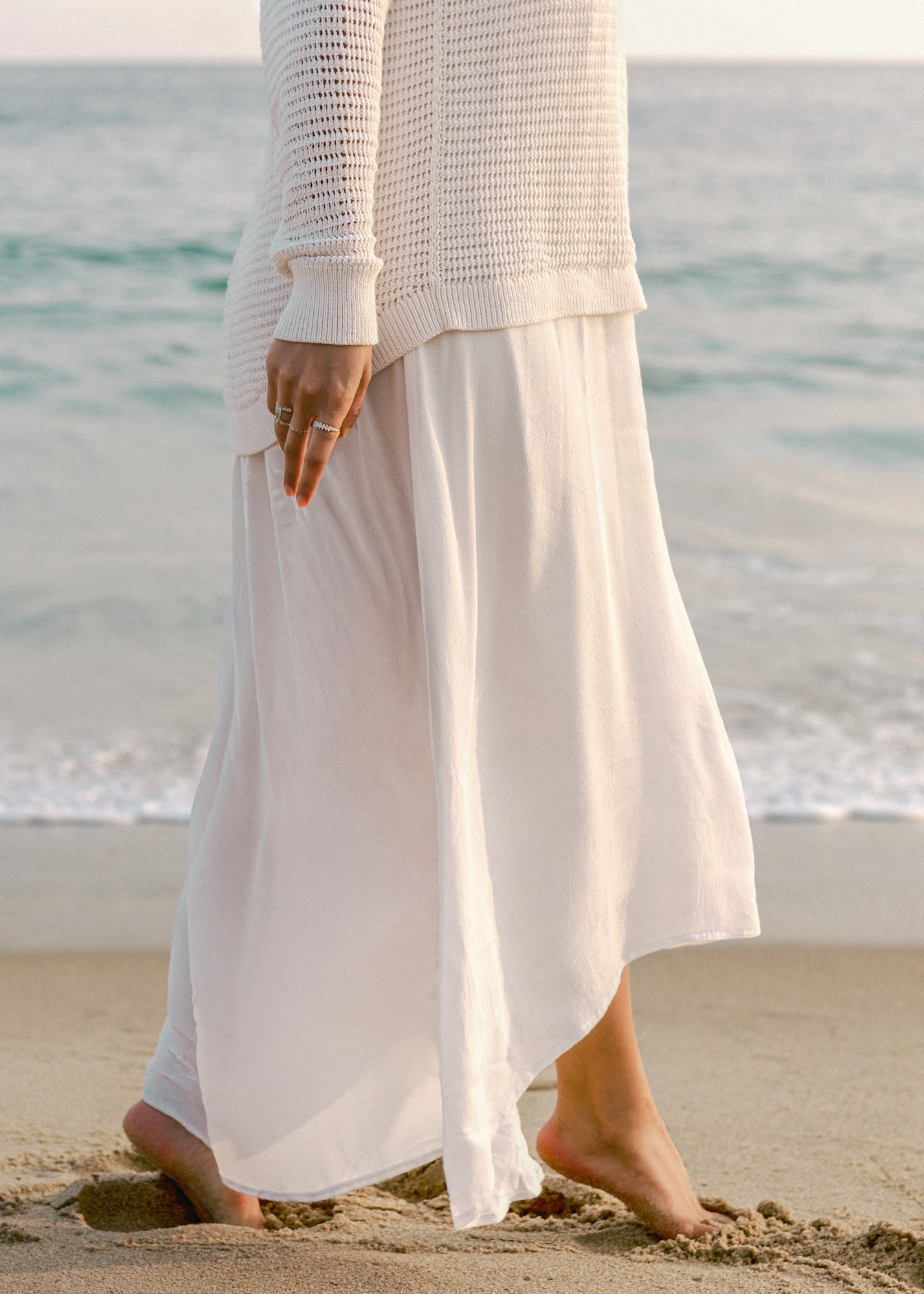 Fashion lookbook photographer capturing model walking on California beach in flowing white skirt and knit sweater | Chelsea Loren Creative Director