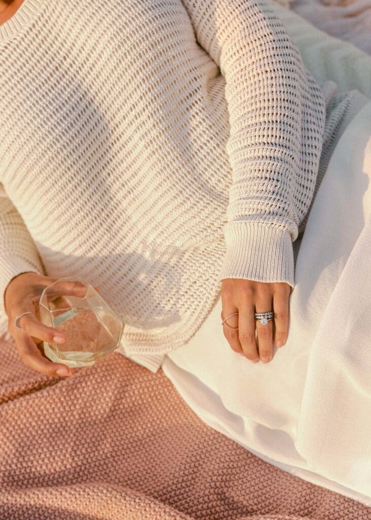 Fashion lookbook detail shot of knit sweater texture with rings and white skirt in golden light | Chelsea Loren Creative Director California