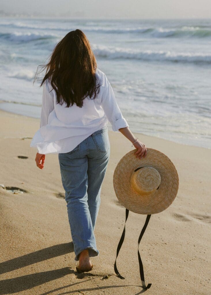 Lifestyle fashion photography back shot of woman walking California beach with straw hat | Chelsea Loren Lookbook Photographer