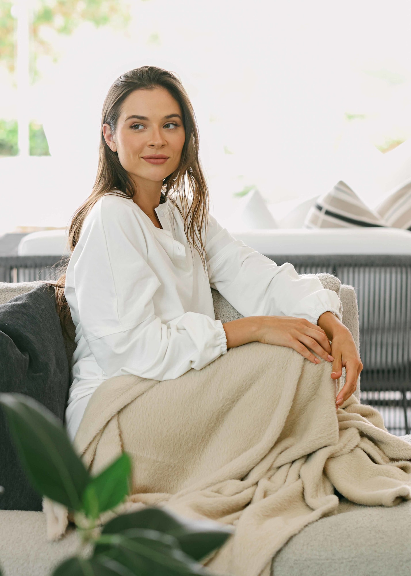 Lifestyle fashion lookbook photo of model seated on outdoor sofa in soft white interior light | Chelsea Loren Photography California