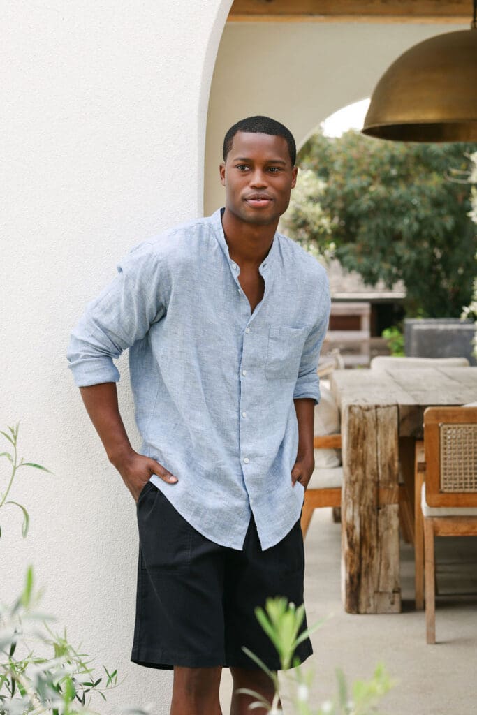 MUJI SS26 women's linen collection – model in blue striped linen dress at ornate wooden archway doorway, editorial lookbook photography by Chelsea Loren