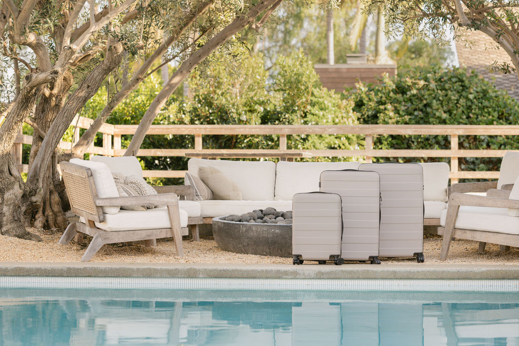 MUJI SS26 hard-shell luggage collection in warm beige – 36L, 75L and 105L sizes styled poolside beneath olive trees, brand photography by Chelsea Loren Carlsbad California