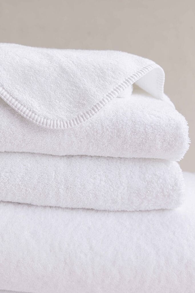 Jennifer Adams white towels stacked in extreme texture close-up on clean neutral background