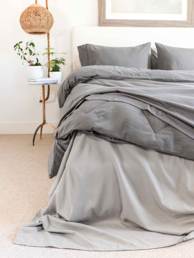 Jennifer Adams plush grey blanket styled on bed in moody bedroom atmosphere with warm lighting