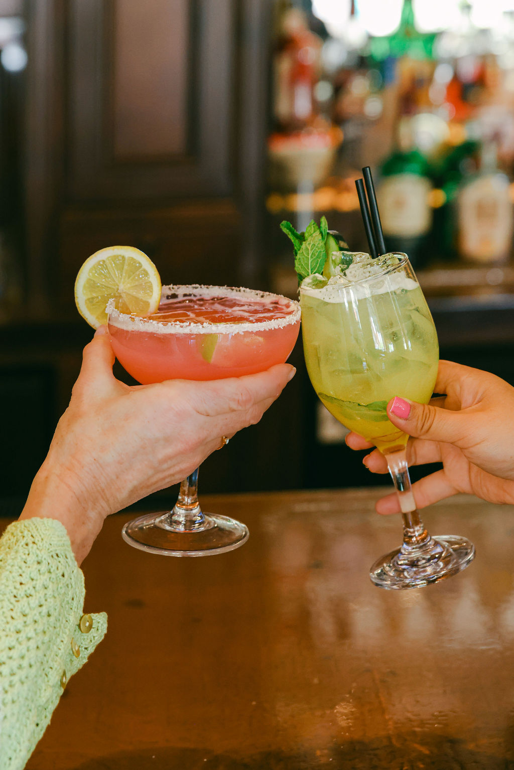 Two cocktails clinking at Brickhouse bar - pink strawberry margarita and green mojito-style drink in Lodi