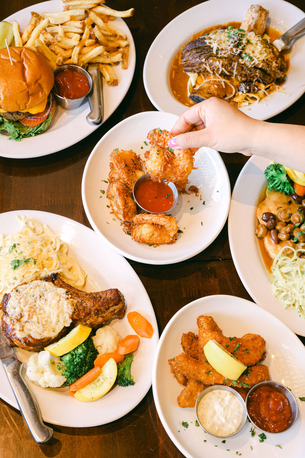 Overhead spread of coconut prawns, pasta, short rib, and chicken plates at Brickhouse Italian Restaurant Lodi