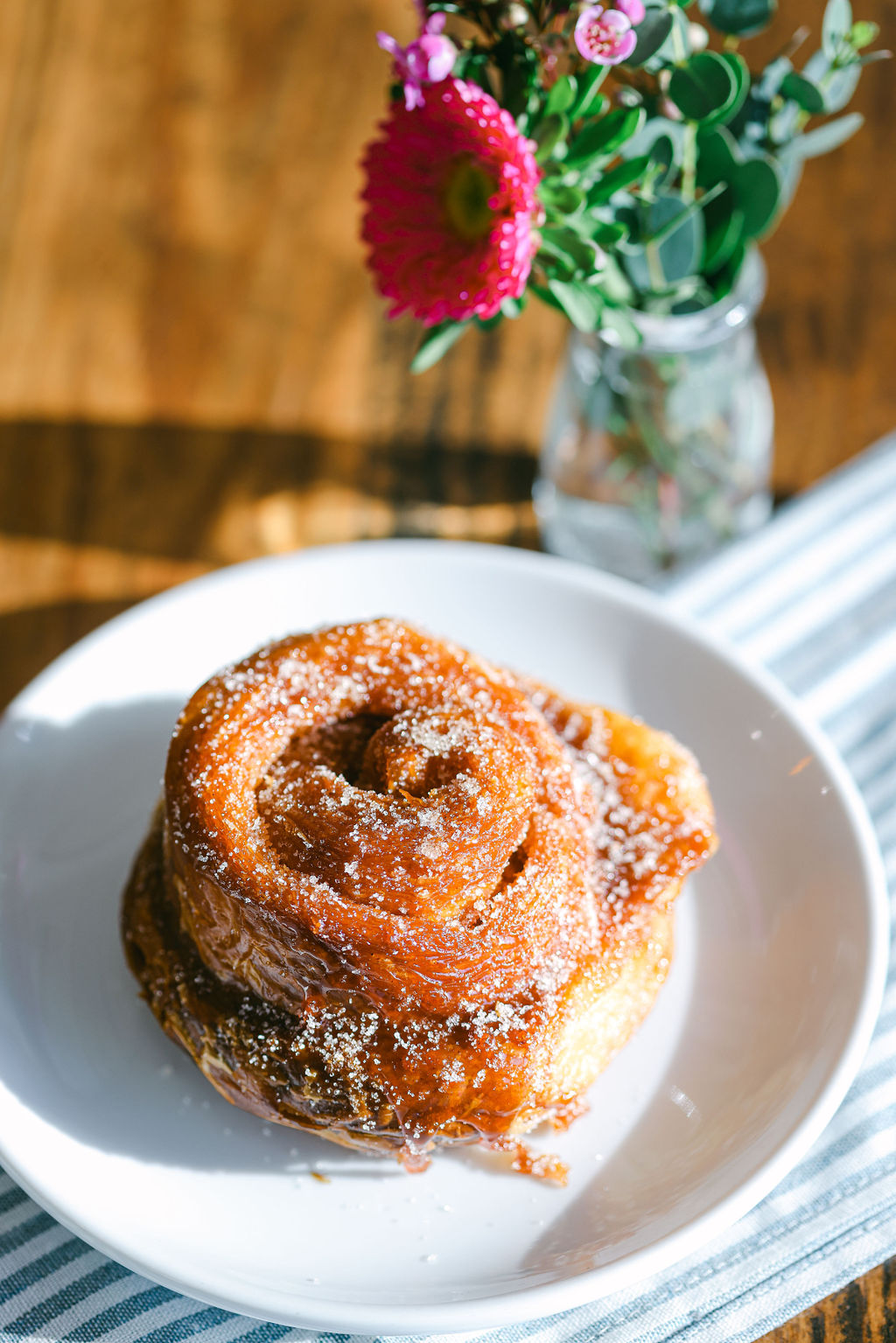 Croissant and coffee held against bright blue tile wall at Ruby's Bakery in Lodi California