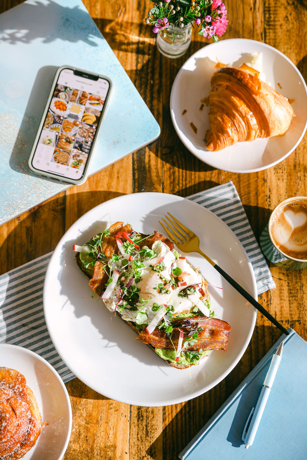 Top-down flatlay of hands reaching for cookies, scone, and danish on marble surface at Ruby's Bakery Lodi