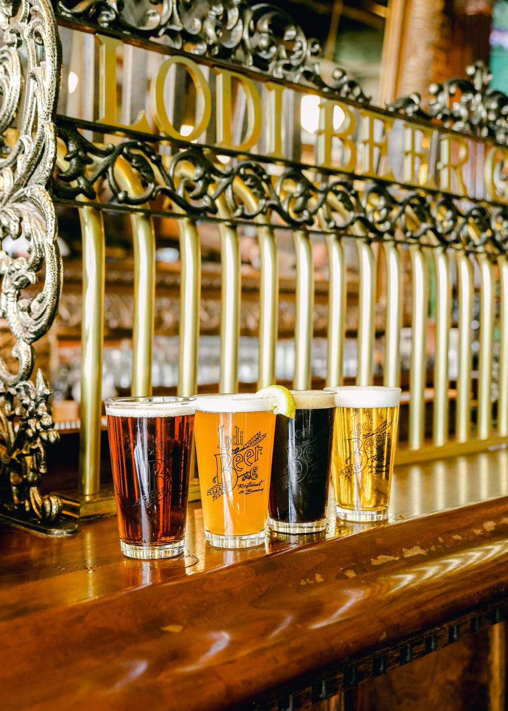 Close-up of Lodi Beer Company pint glass filled with golden beer and lemon wedge against black background