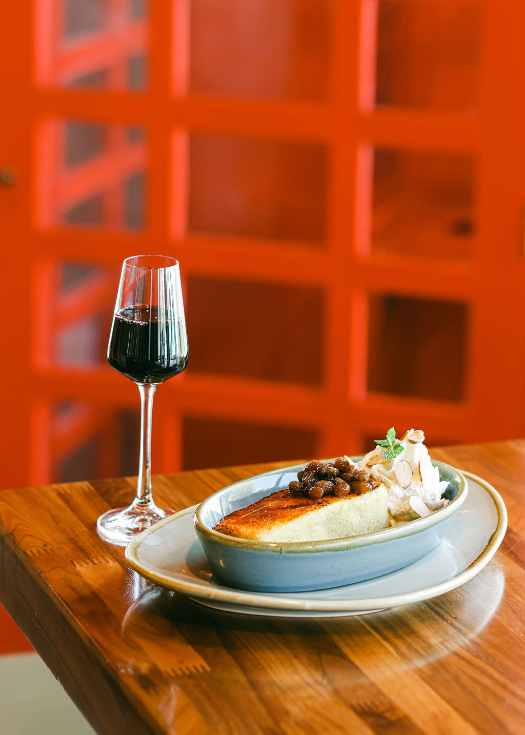 Bartender reaching up rolling library ladder on wall of backlit spirits at The Oxford Kitchen in Lodi California