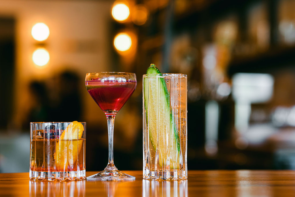 Two hands clinking Lodi Beer Company pint glasses in front of ornate gold signage