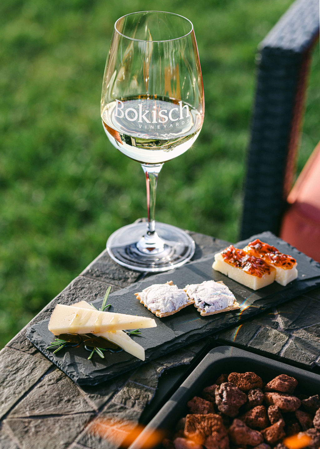 Woman holding Bokisch Vineyards wine glass toward golden sunset light with vineyard stretching into distance in Lodi