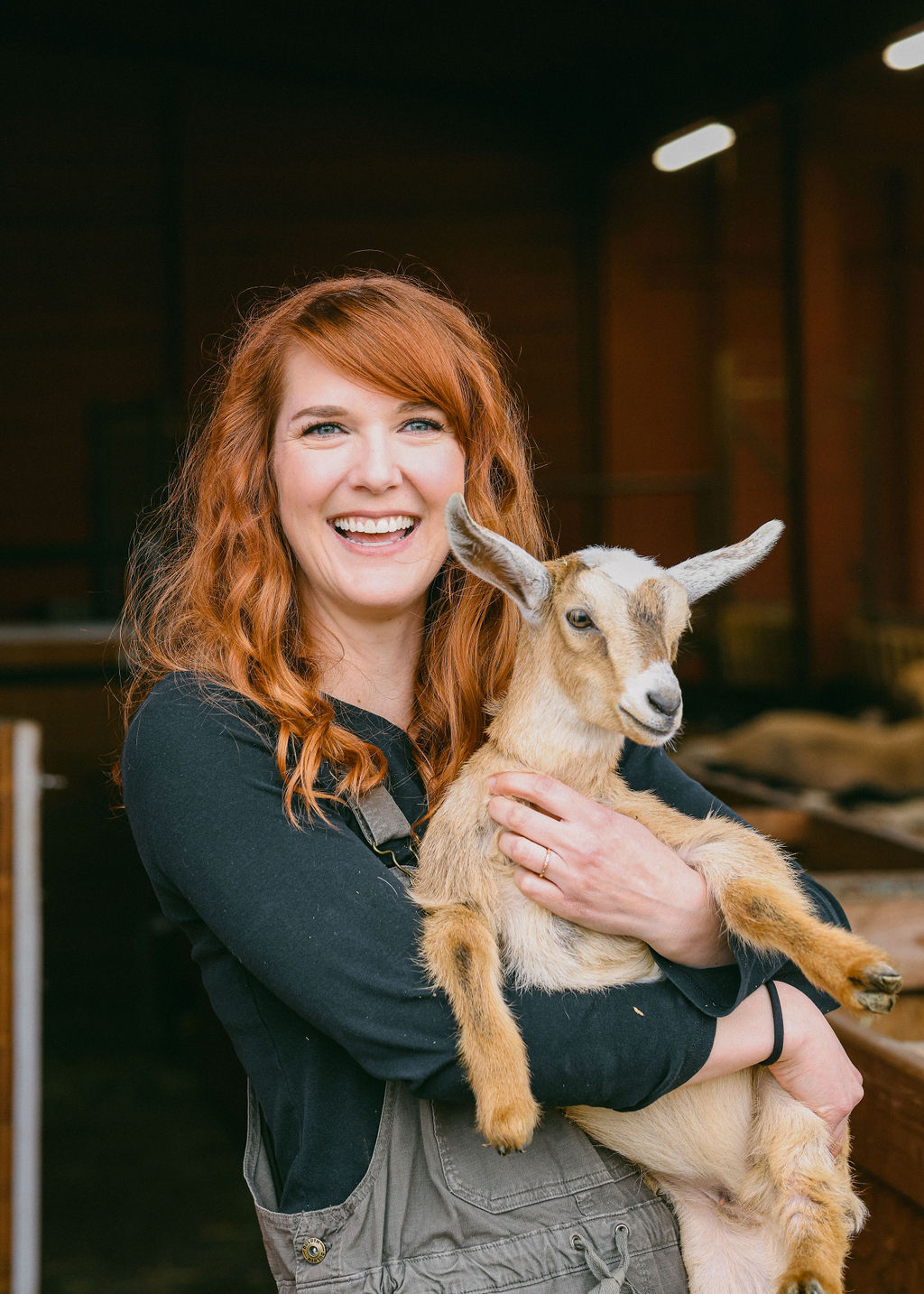 Woman laughing while holding a baby goat at Spenker Family Farm Goodnight Goats experience in Lodi California
