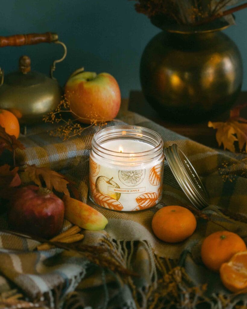 Cozy fall candle flat lay with dark moody styling plaid textile and autumn seasonal fruit